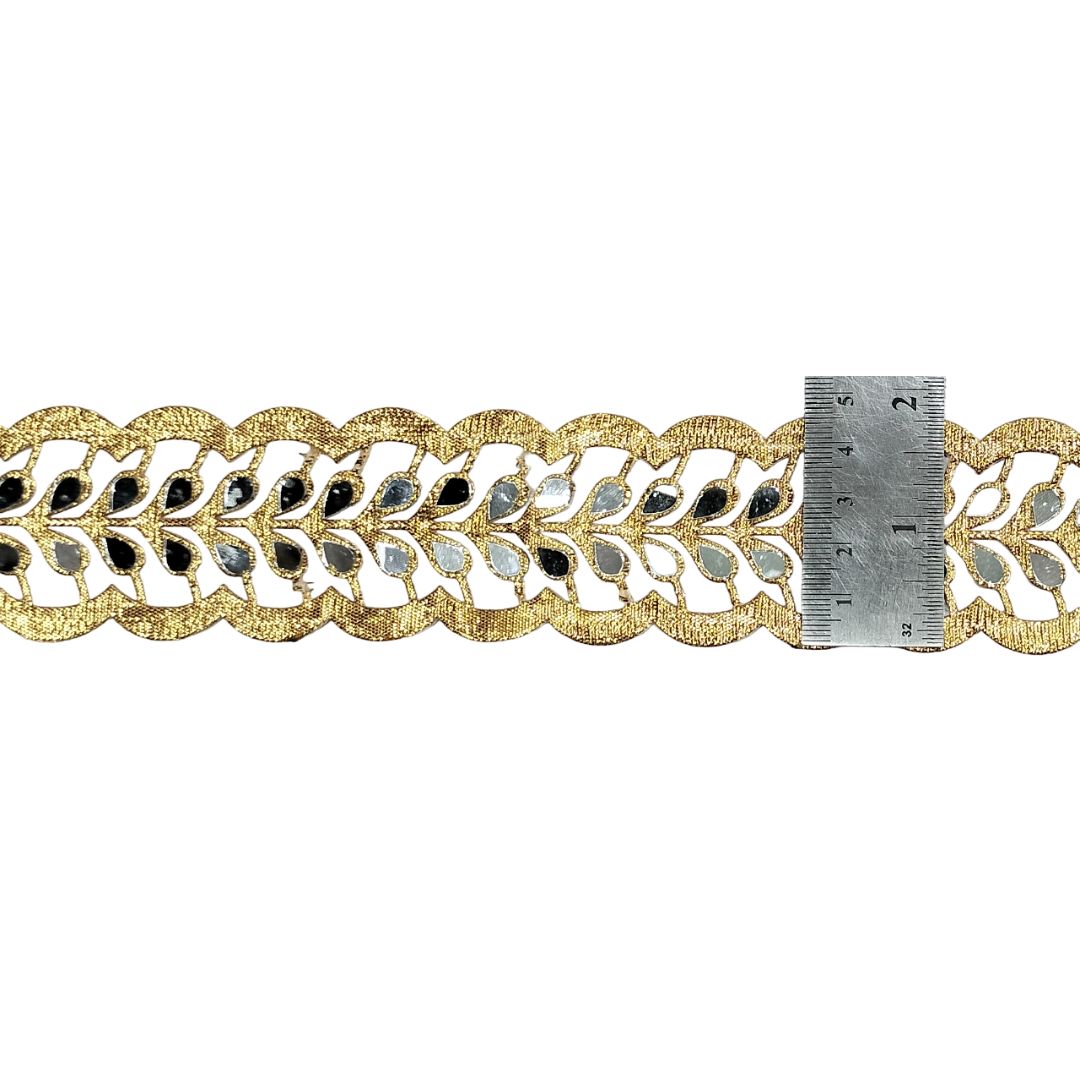 Decorative gold lace trim with a ruler for scale on a white background